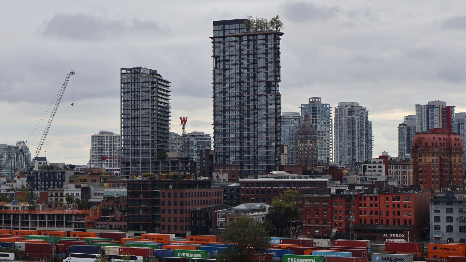Urban cityscape of downtown Vancouver, showcasing skyscrapers and a train yard under cloudy skies.