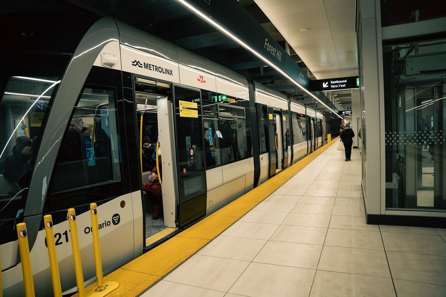 Interior of a Toronto subway station with a Metrolinx train and passengers boarding.